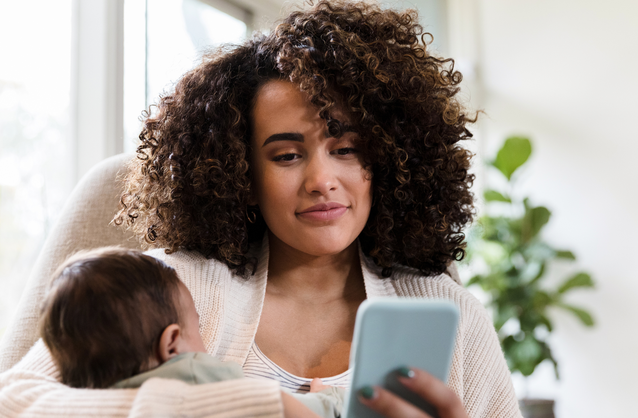 New mom uses smarphone at home stock photo