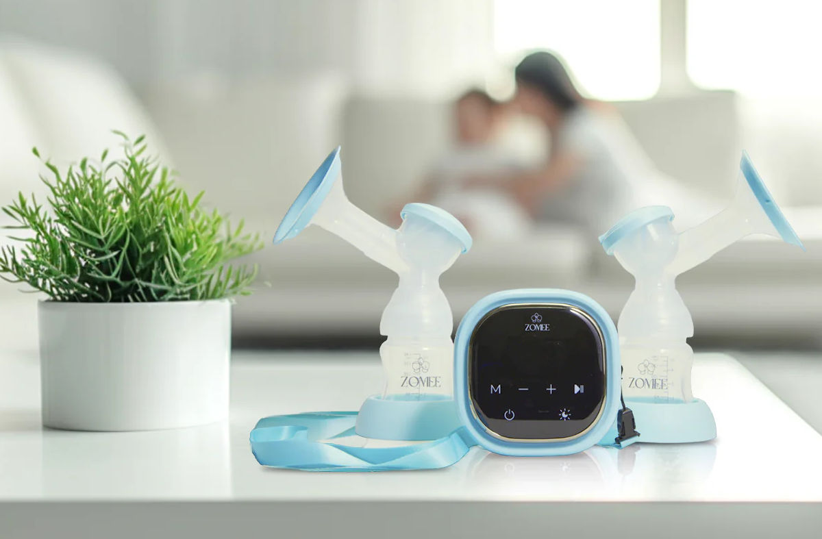 Zomee Breast Pumps on a kitchen counter with mom and baby in the background