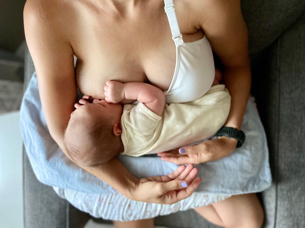 A mother breastfeeding her newborn while holding them close, demonstrating the bond and benefits of breastfeeding. This image highlights the combination of breastfeeding and breast pumping as options for nourishing a baby.