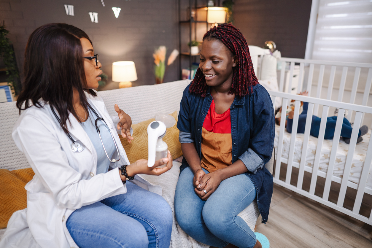 An nurse sitting in a mother's nursery Defining hospital-grade breast pumps to the mother while holding the breast pump