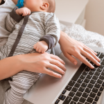 Mother working on a laptop while holding her baby, illustrating multitasking and the convenience of hands-free pumping technology for busy parents.