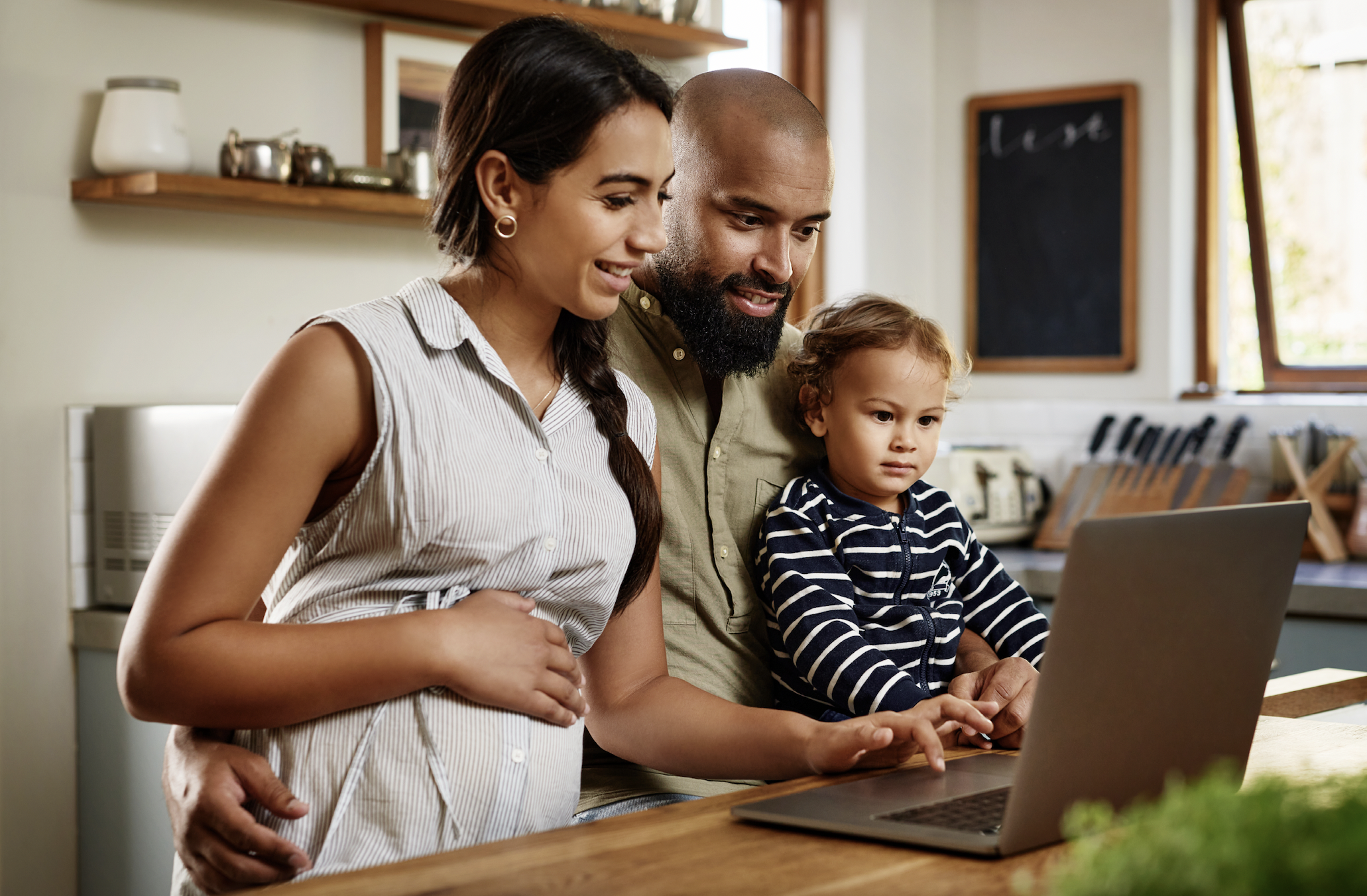 African American mom, dad and baby looking at computer screen in the kitchen searching for the Medela Pump in Style