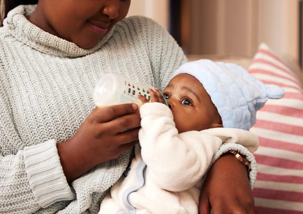 mother holding infant feeding it from a bottle